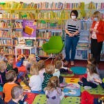 Grupa dzieci w bibliotece podczas głośnego czytania