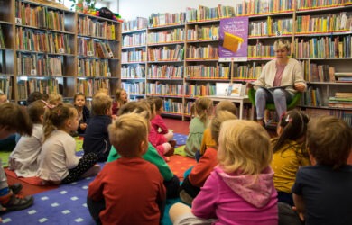 Grupa dzieci podczas głośnego czytania w bibliotece