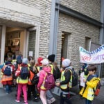 Grupa dzieci z transparentem wchodzi do biblioteki